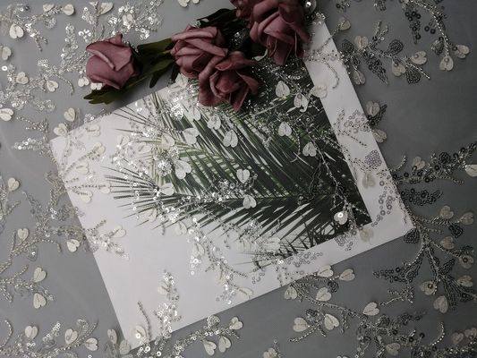 女性の衣服の白いスパンコールはビーズの刺繍の生地をひもで締める