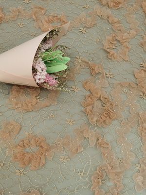 かぎ針編みのきらめきのテュルのピンクの花の網の輝いたレースの生地
