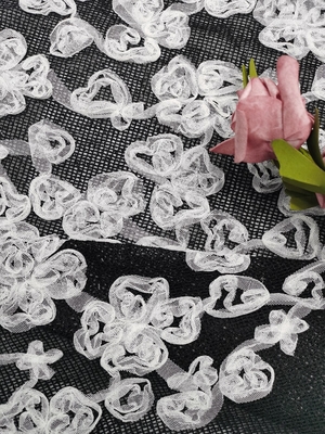 白く黒い対照色の花によって刺繍されるレースの生地のアップリケ